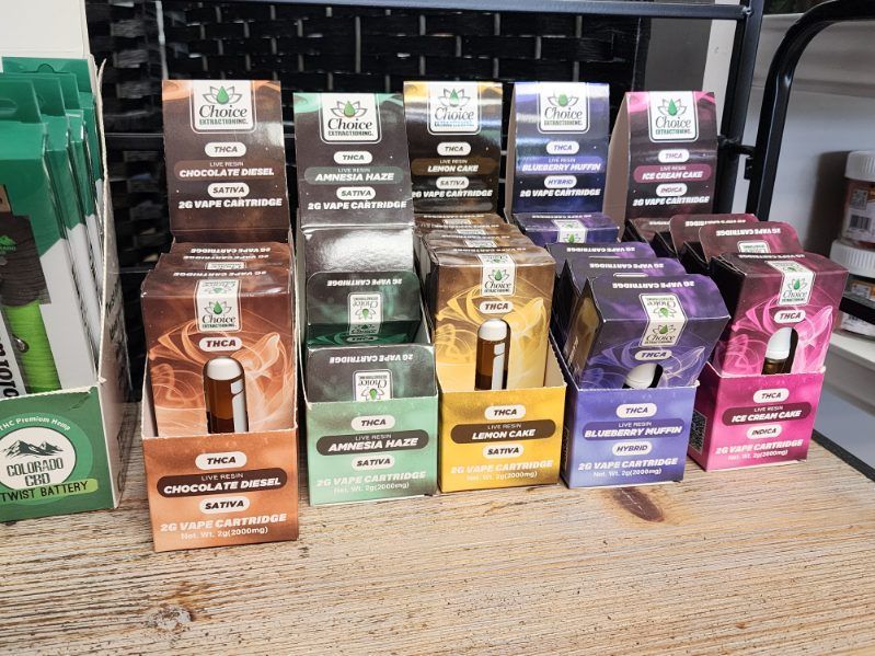 Display of various Oloru Oil products in boxes, featuring different scents, colors, and labels on a store shelf.