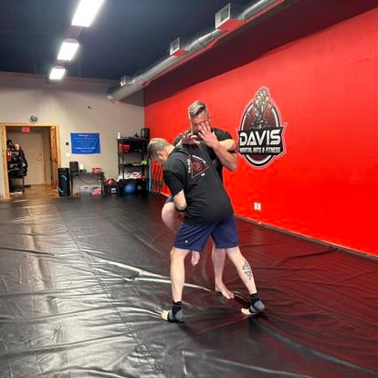 Two men are wrestling on a mat in a gym.