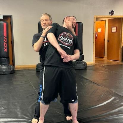 Two men are standing next to each other on a mat in a gym.