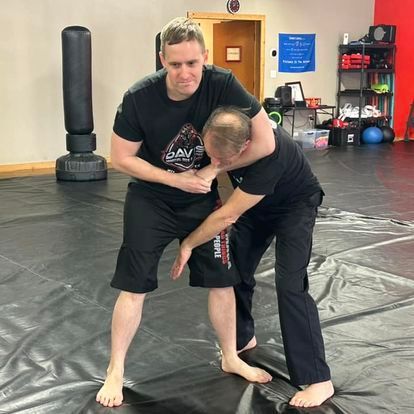 Two men are wrestling on a mat in a gym.