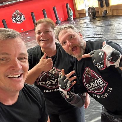 A man and two women are posing for a picture while wearing davis shirts.