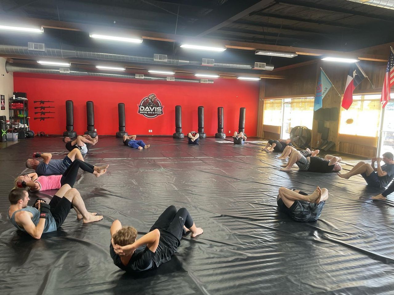 A group of people are doing exercises on a mat in a gym.