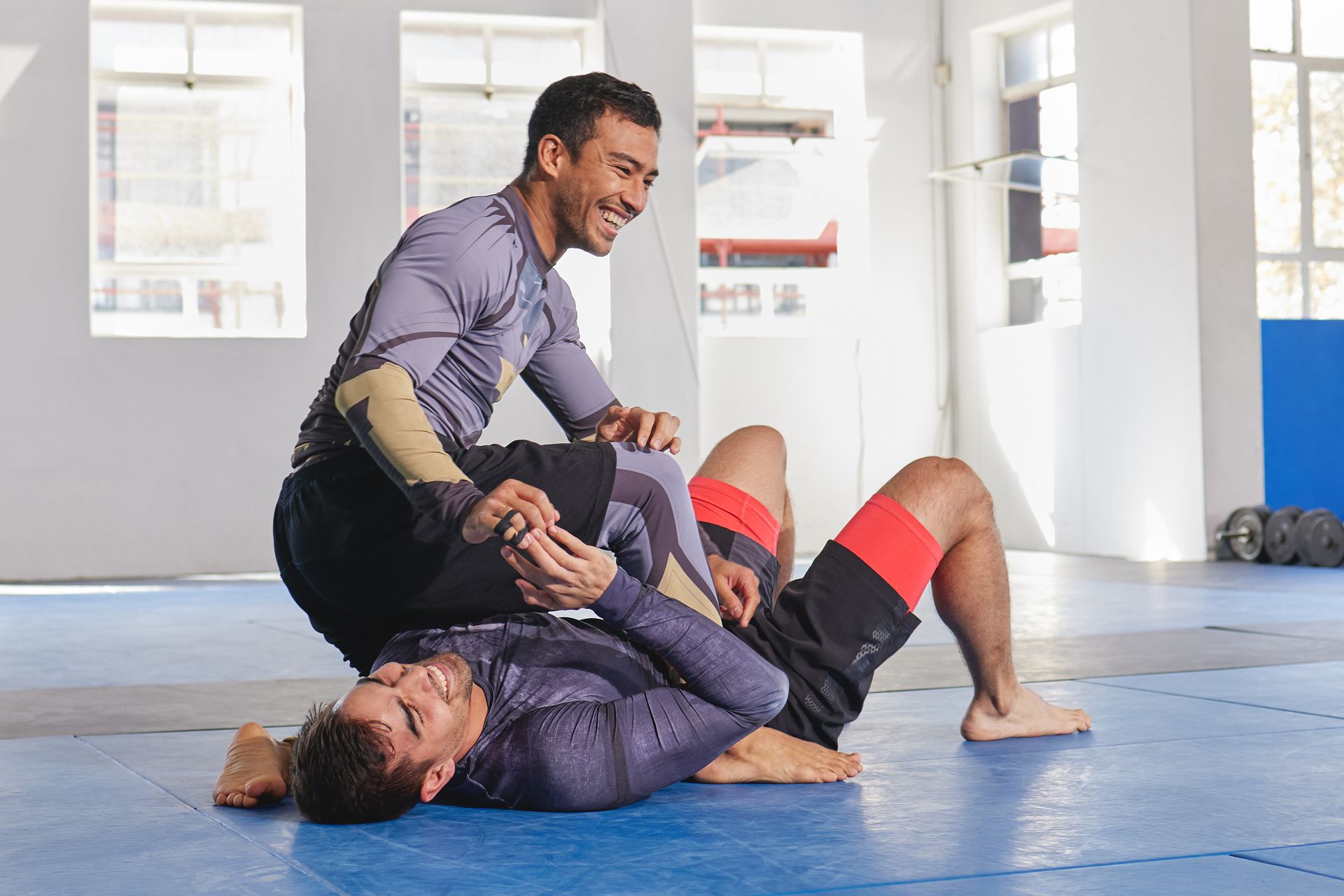 Two men are wrestling on a mat in a gym.