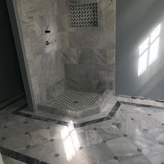 A bathroom with a walk in shower and a marble floor.  Bathroom Remodeling New Orleans