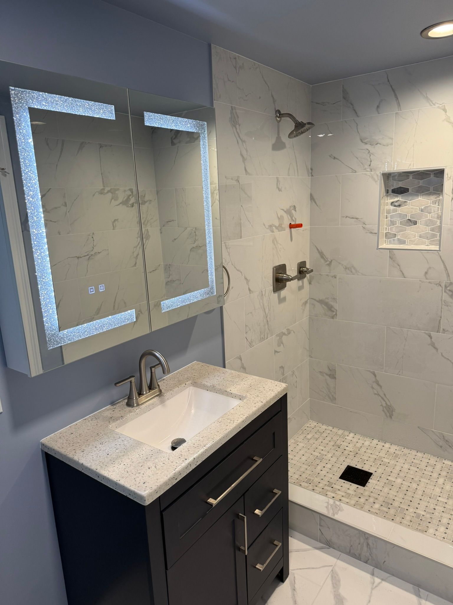 A bathroom with a sink a mirror and a walk in shower Affordable Bathroom Remodeling New Orleans