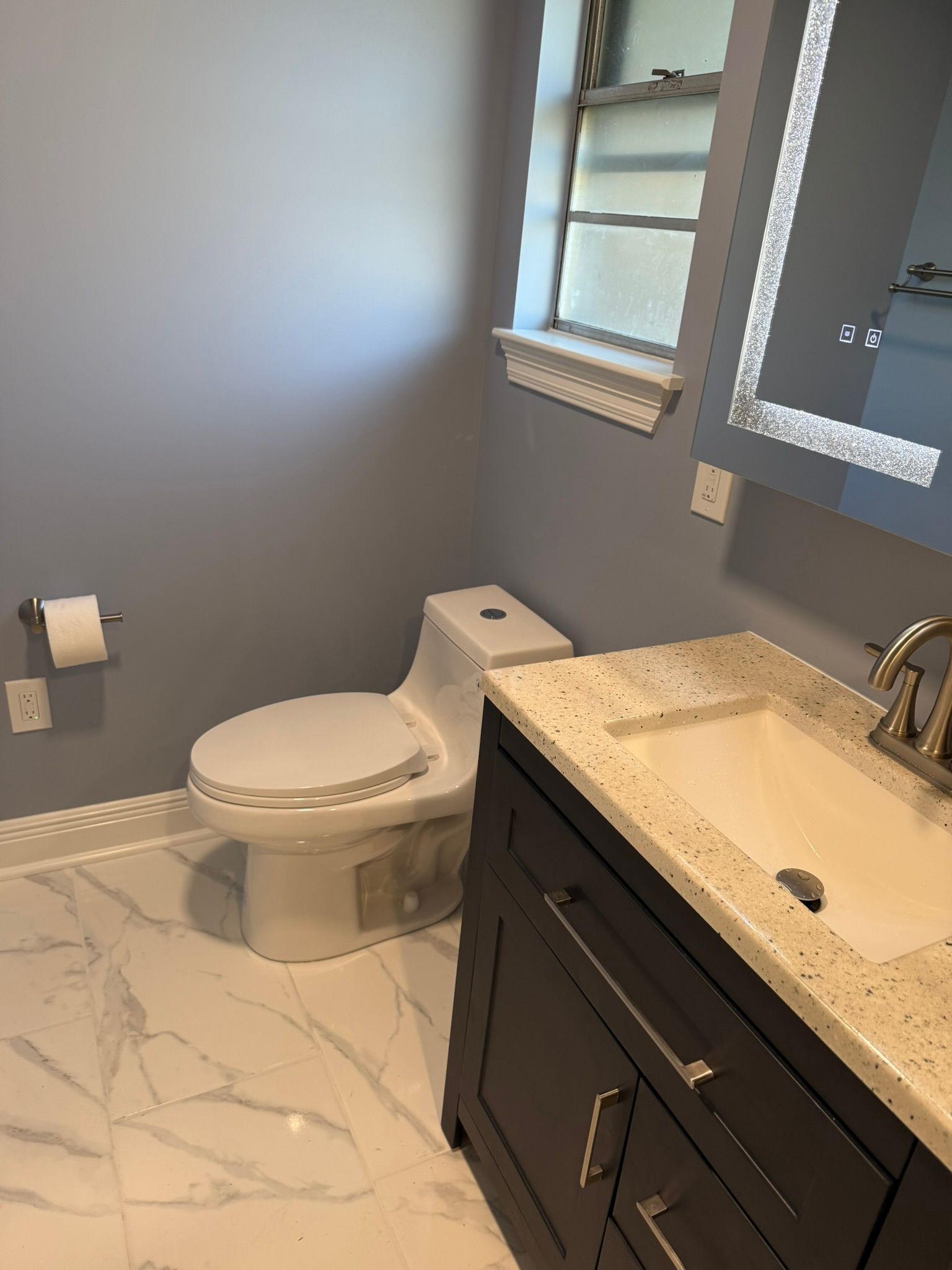 A bathroom with a toilet a sink and a mirror Bathroom Renovation New Orleans LA