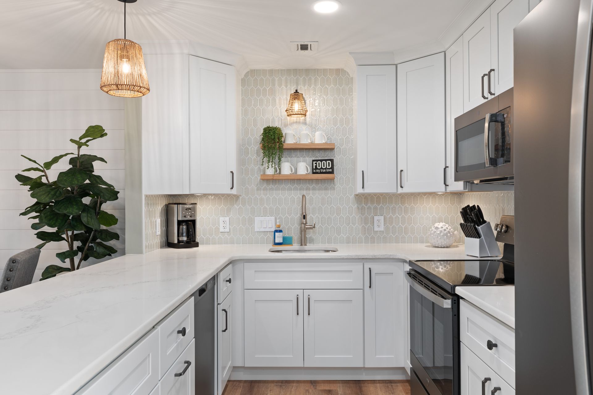 A kitchen with white cabinets , stainless steel appliances , a sink , and a refrigerator.