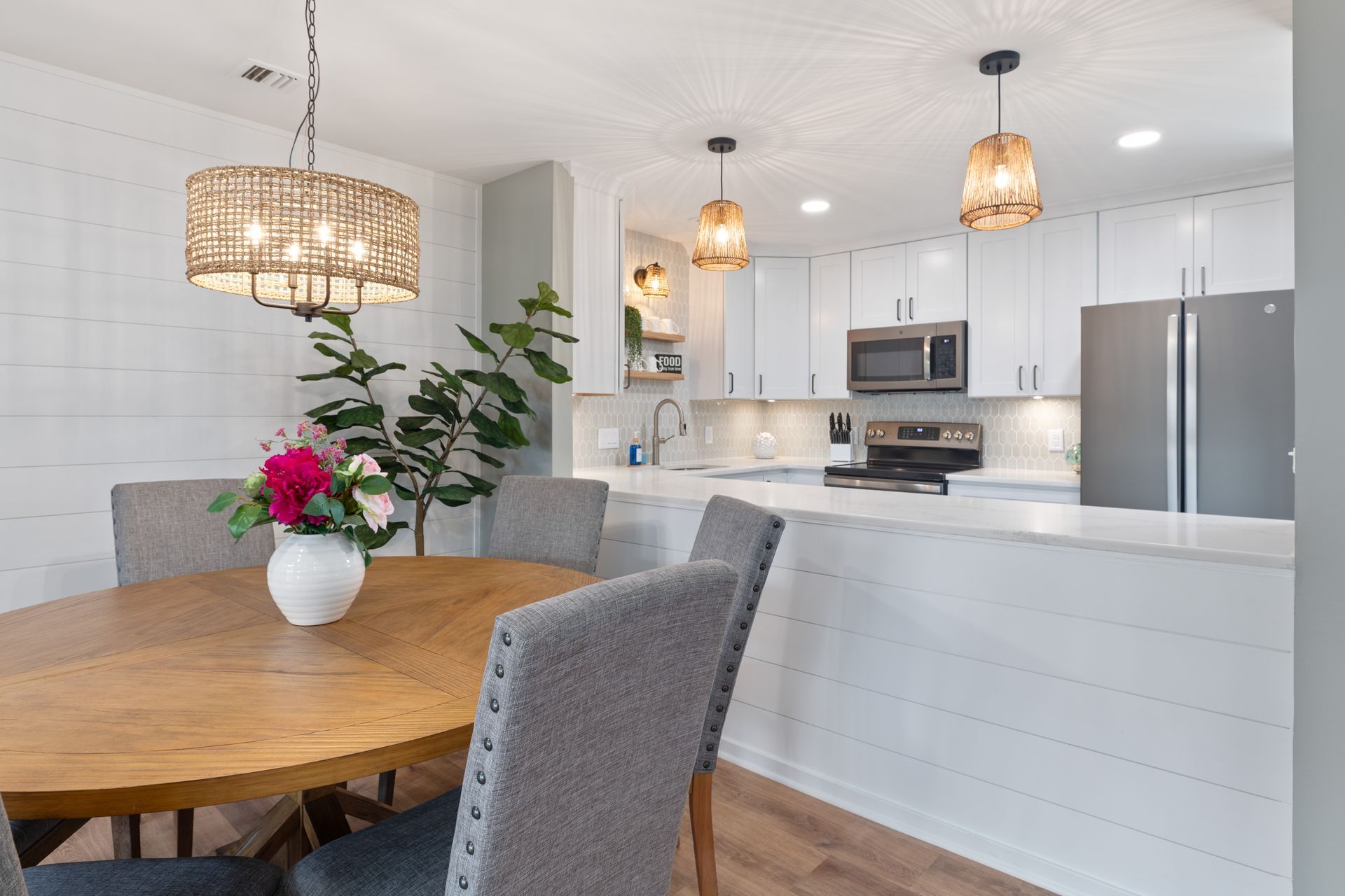 A kitchen with a table and chairs and a vase of flowers on the table.