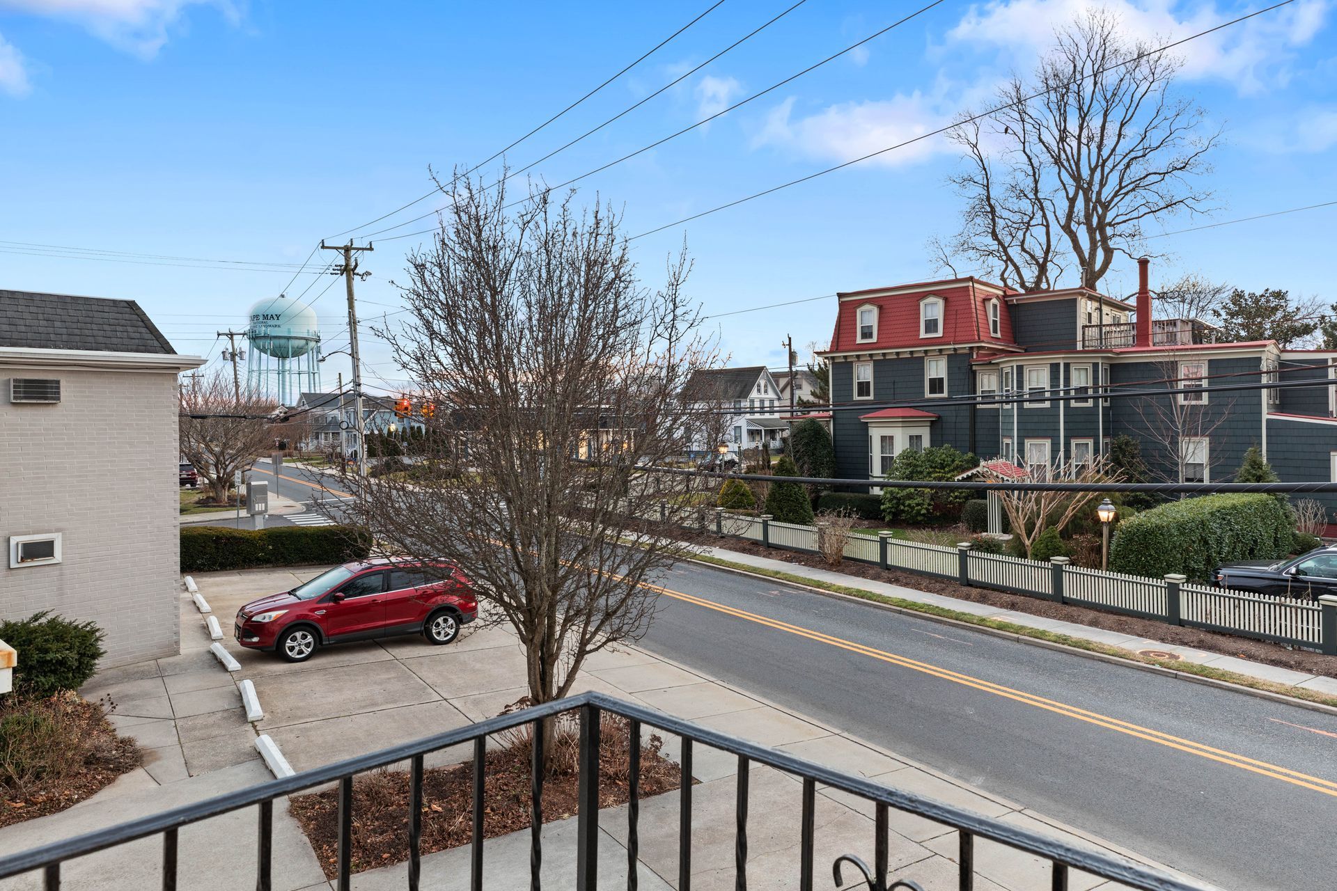 A red car is parked on the side of the road in front of a building.