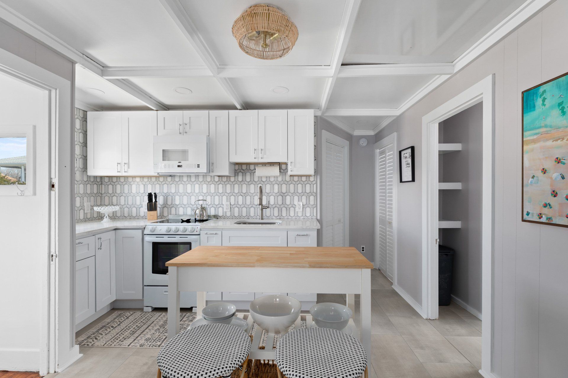 Cape May  Bayside Love rental  kitchen with white cabinets , a wooden table and a stove.