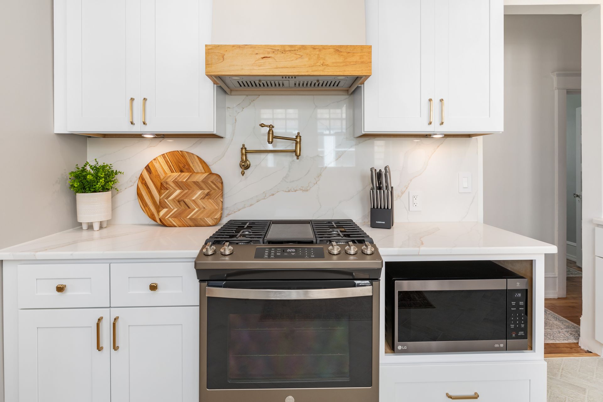 A kitchen with white cabinets , a stove and a microwave.