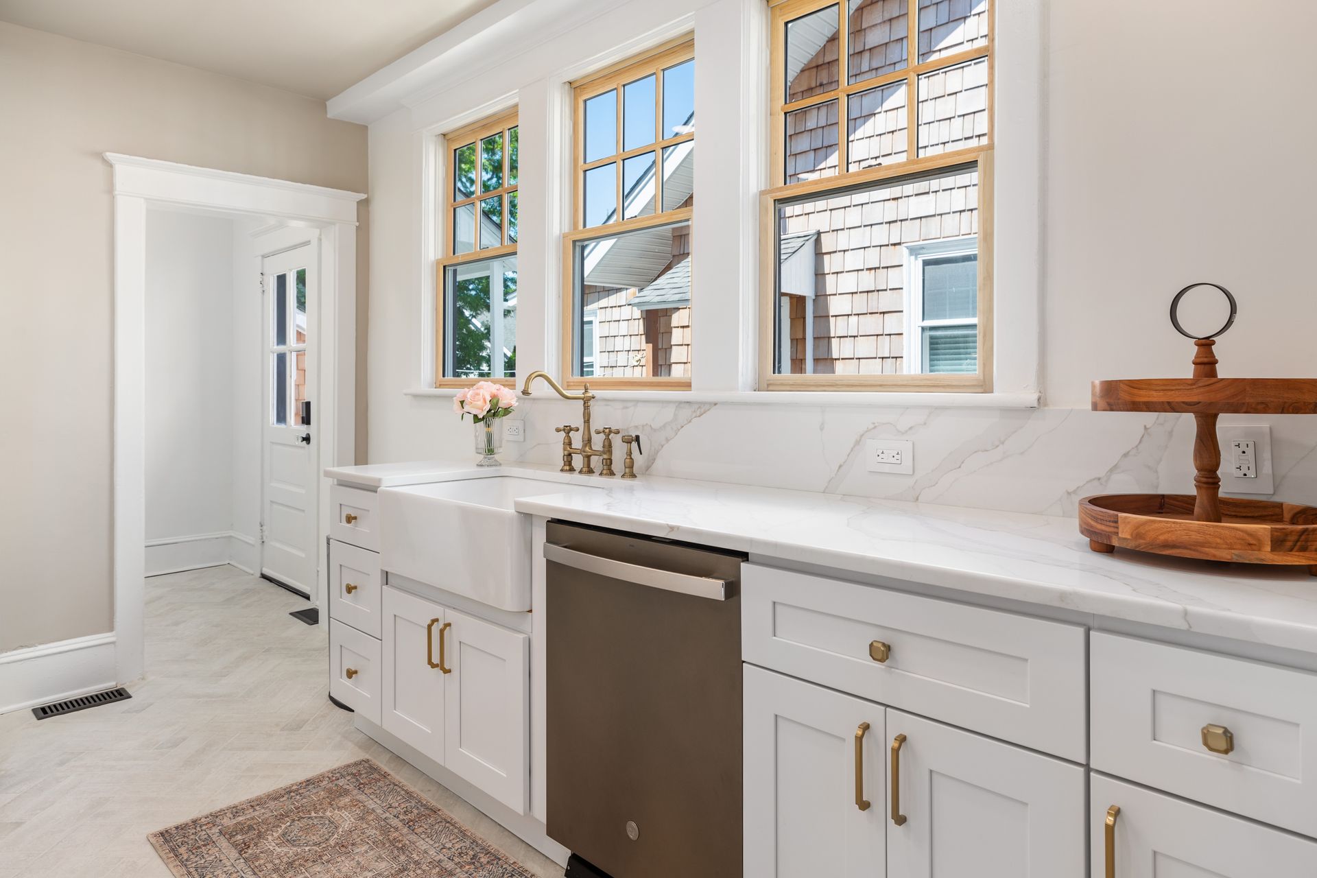 A kitchen with white cabinets , a sink , and a dishwasher.