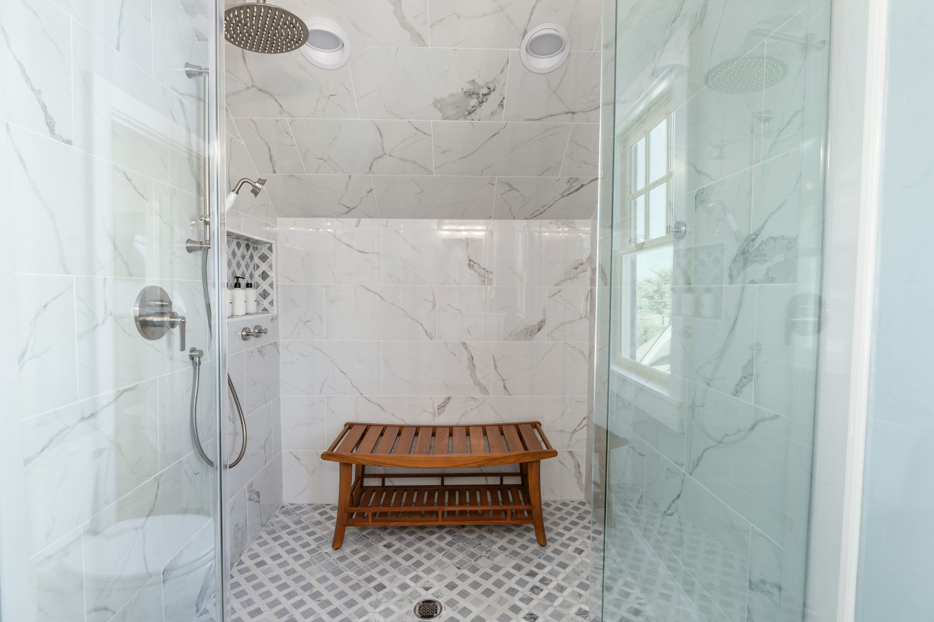 A bathroom with a walk in shower and a wooden bench.