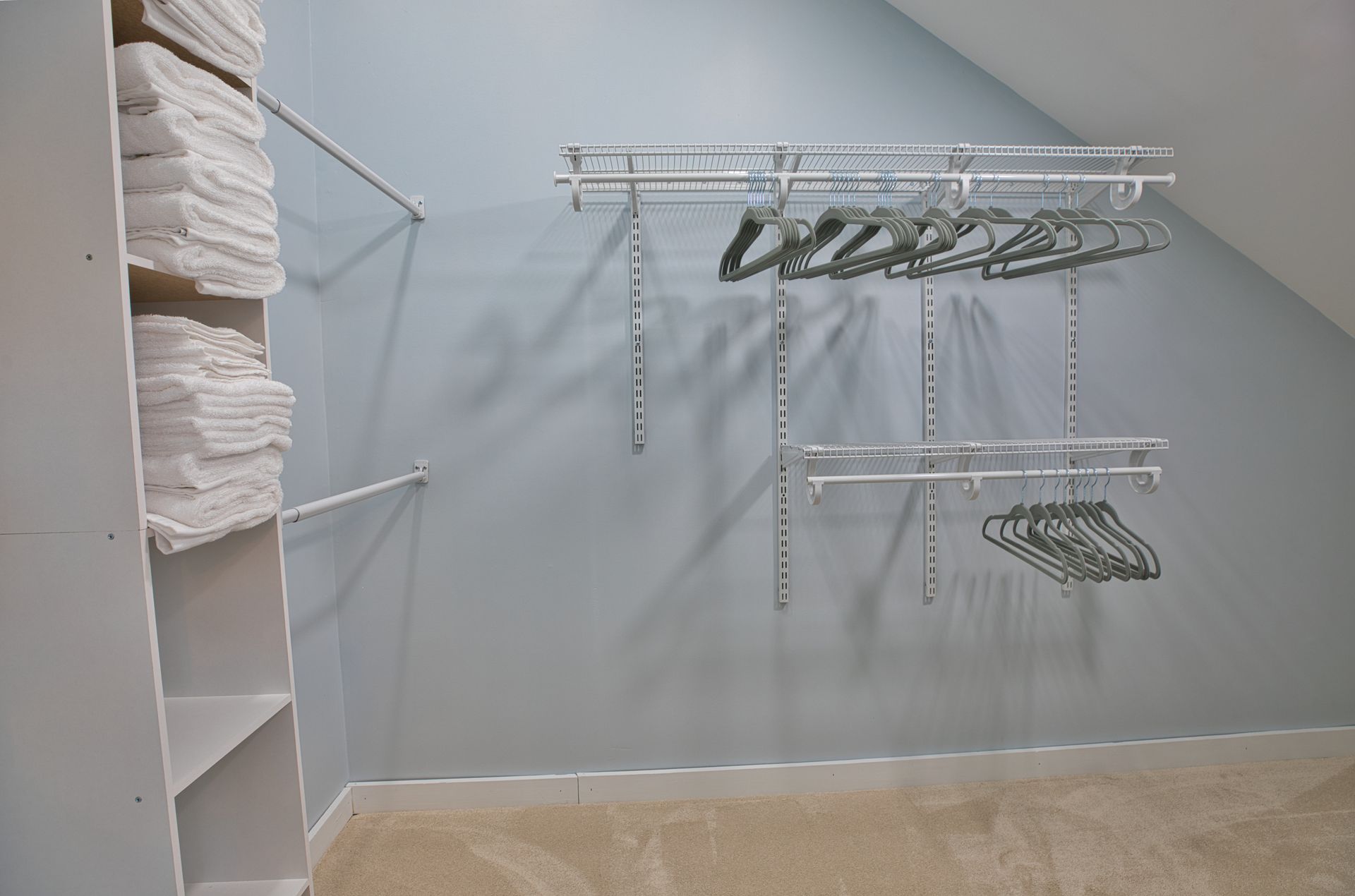 A walk in closet with a slanted ceiling and clothes racks