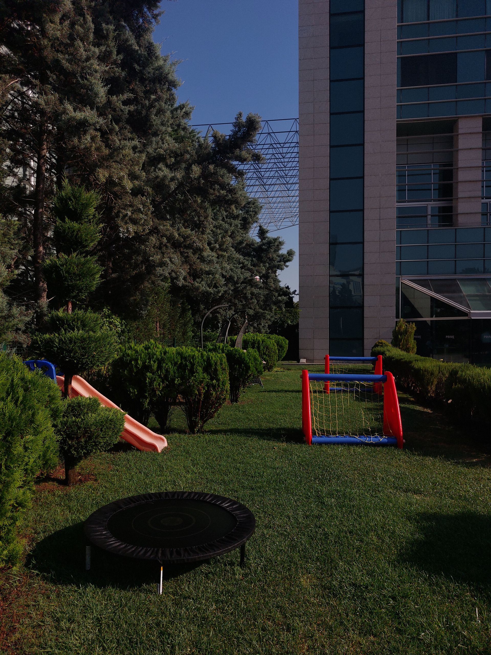 A playground with a slide and a trampoline in front of a building