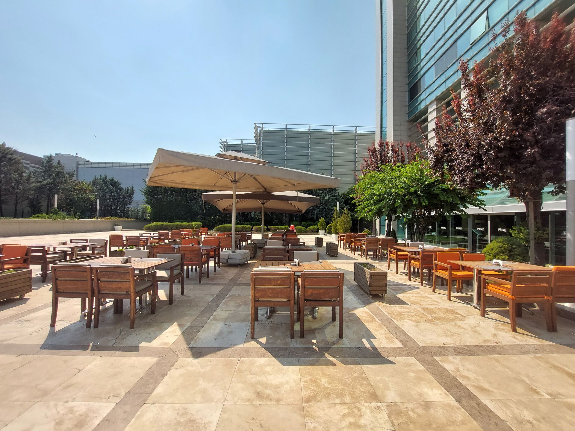 A patio with tables and chairs and umbrellas in front of a building.