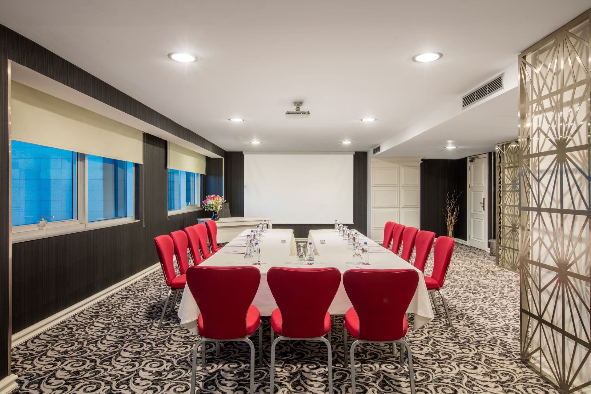 A conference room with a long table and red chairs.