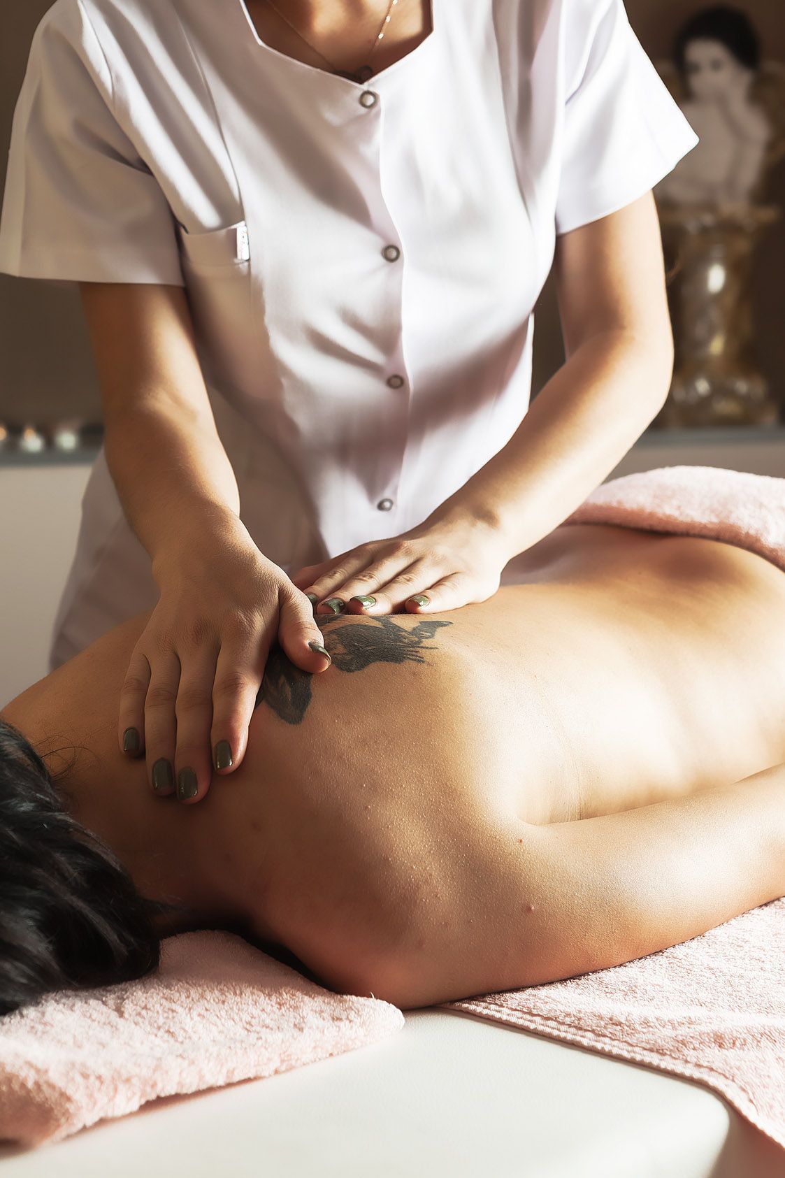 A woman is giving a massage to a man with a tattoo on his back.
