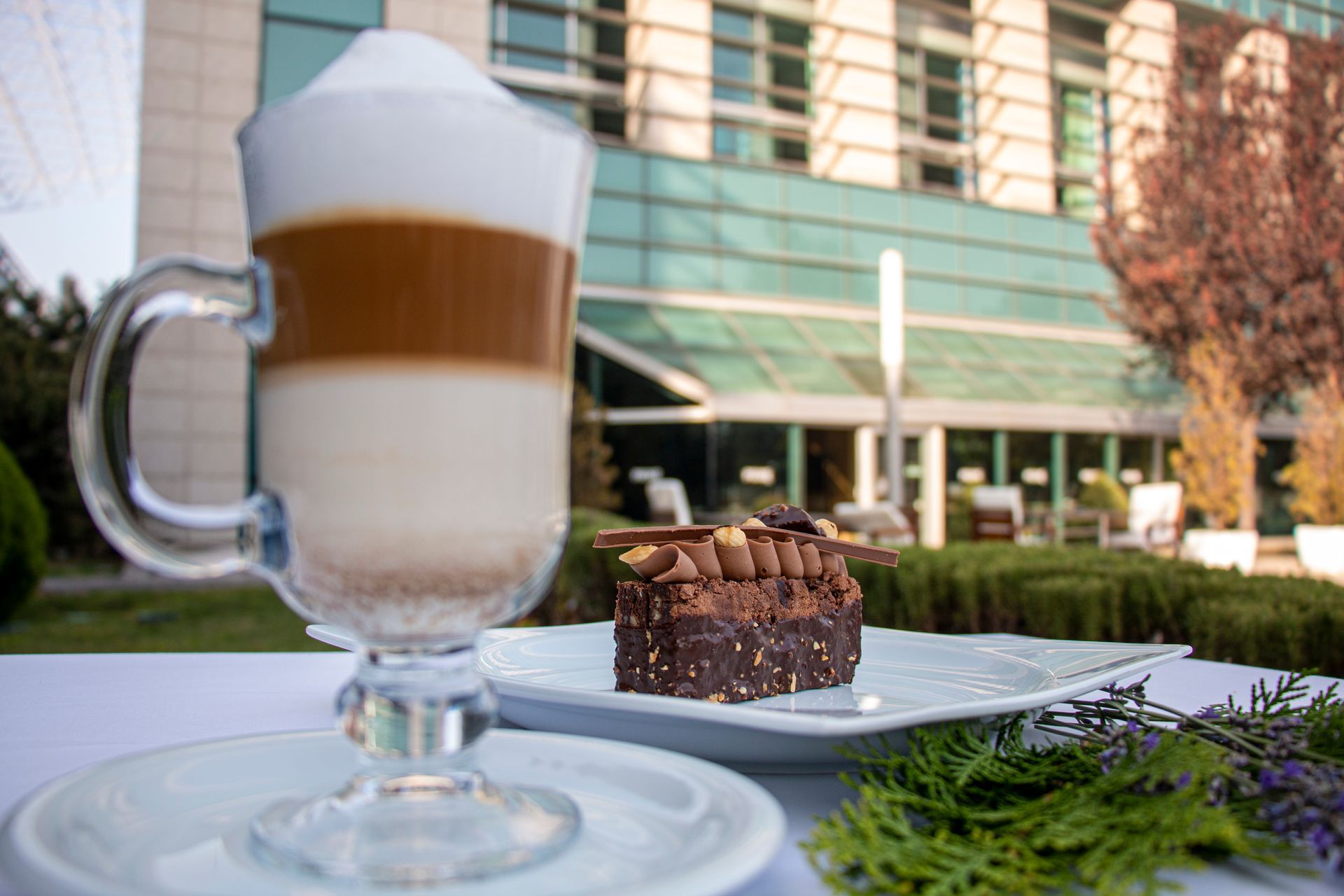 A cup of coffee and a brownie on a plate on a table.