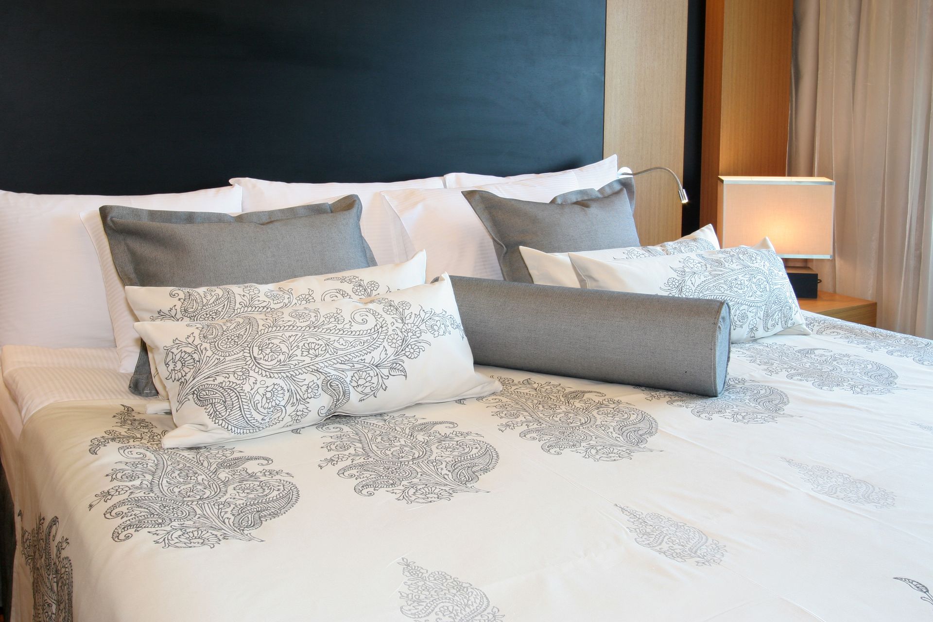 A bed with a white comforter and grey pillows