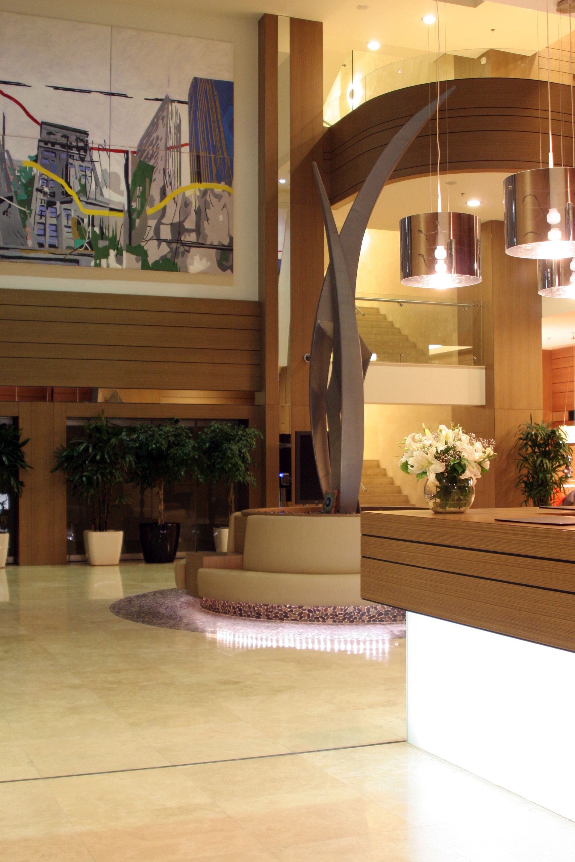 A hotel lobby with a large painting on the wall above the reception desk