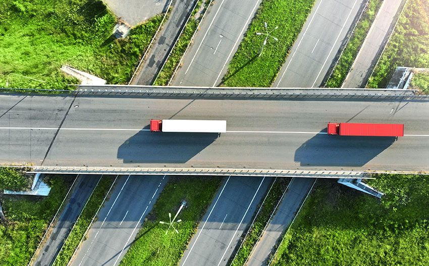 An aerial view of two semi trucks driving on a highway.