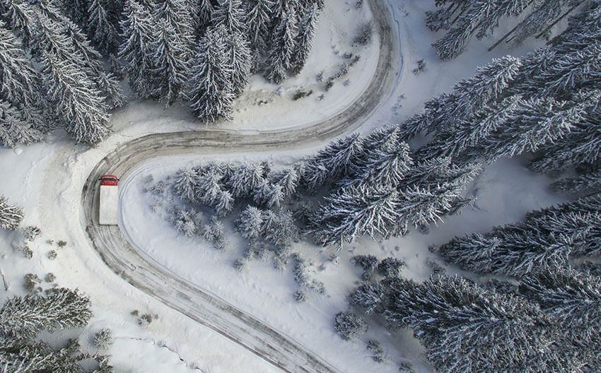 An aerial view of a truck driving down a snowy road.