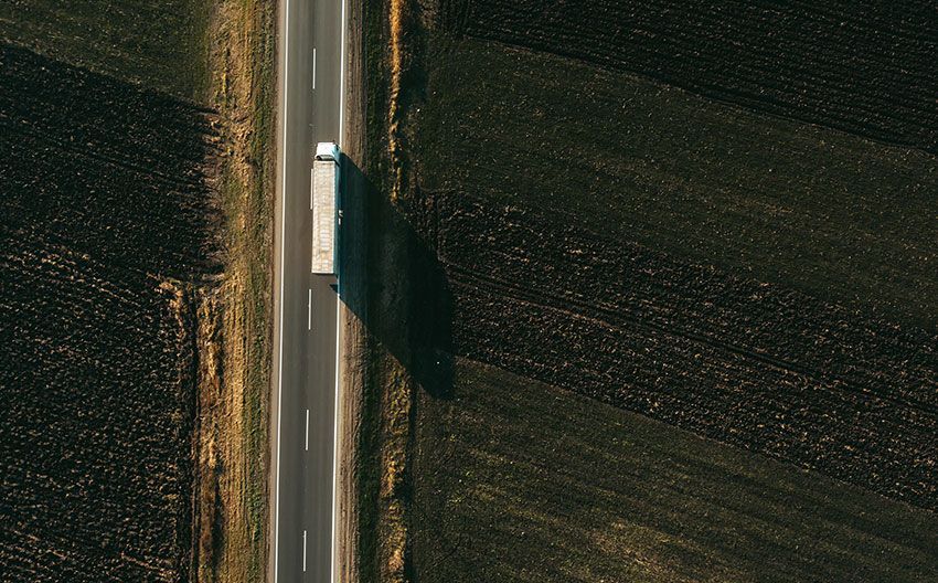 An aerial view of a truck driving down a country road.