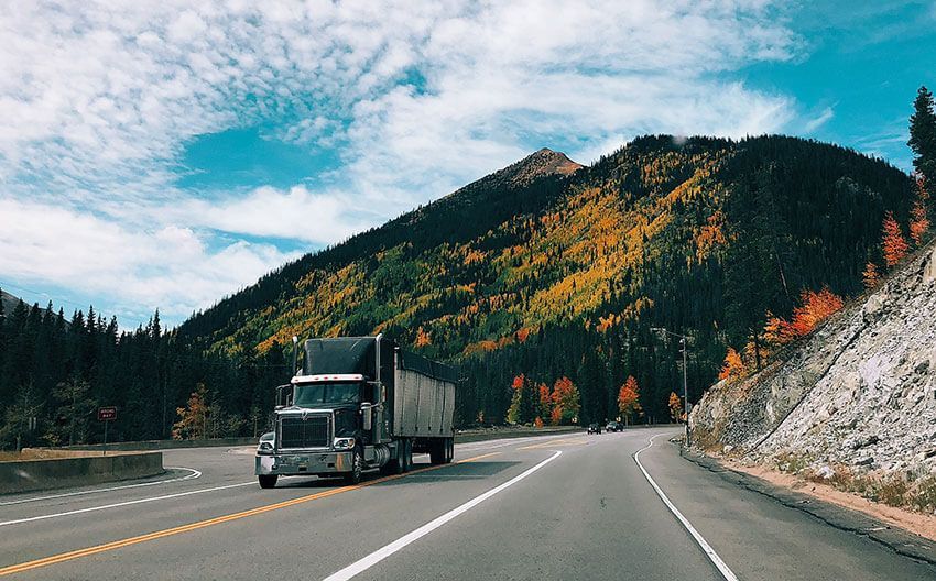 A semi truck is driving down a mountain road.