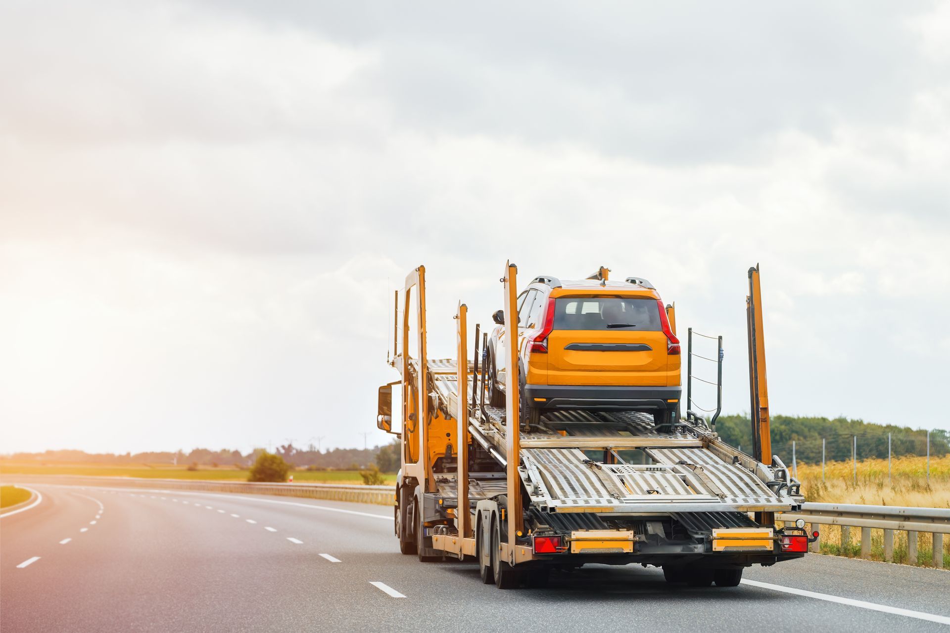 A truck is carrying a car on a highway.