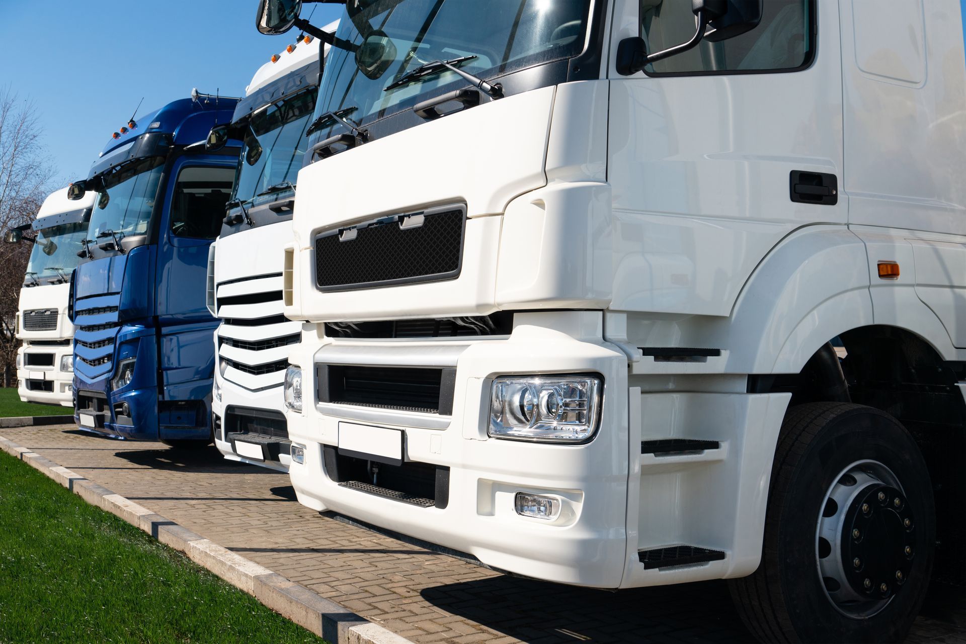 A row of semi trucks parked next to each other in a parking lot.