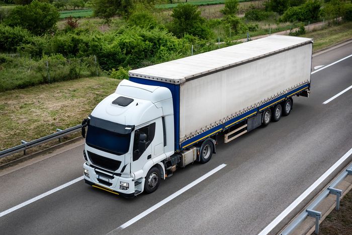 A white semi truck is driving down a highway.