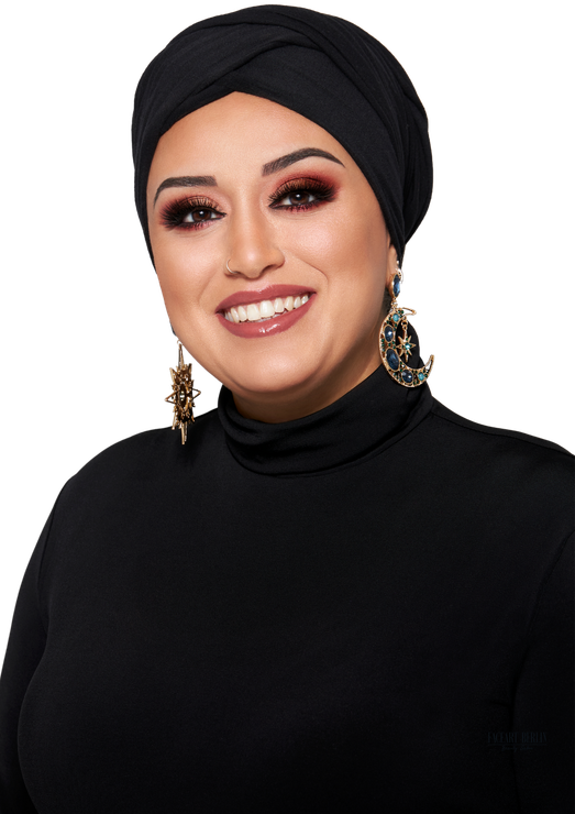 Eine Frau mit Turban und Ohrringen lächelt in die Kamera