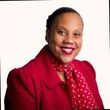 Woman in red blazer and polka-dot scarf smiles.