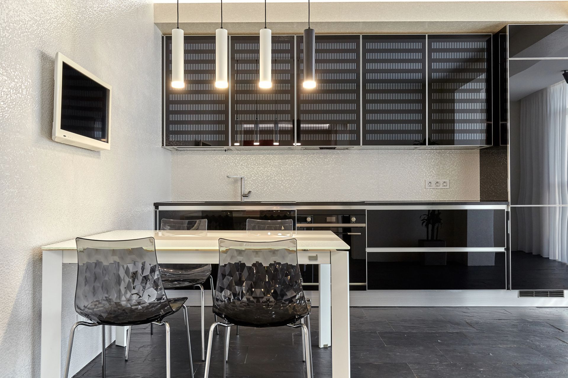 Cucina moderna in bianco e nero con illuminazione dall'alto, mobili e un tavolo con due sedie.