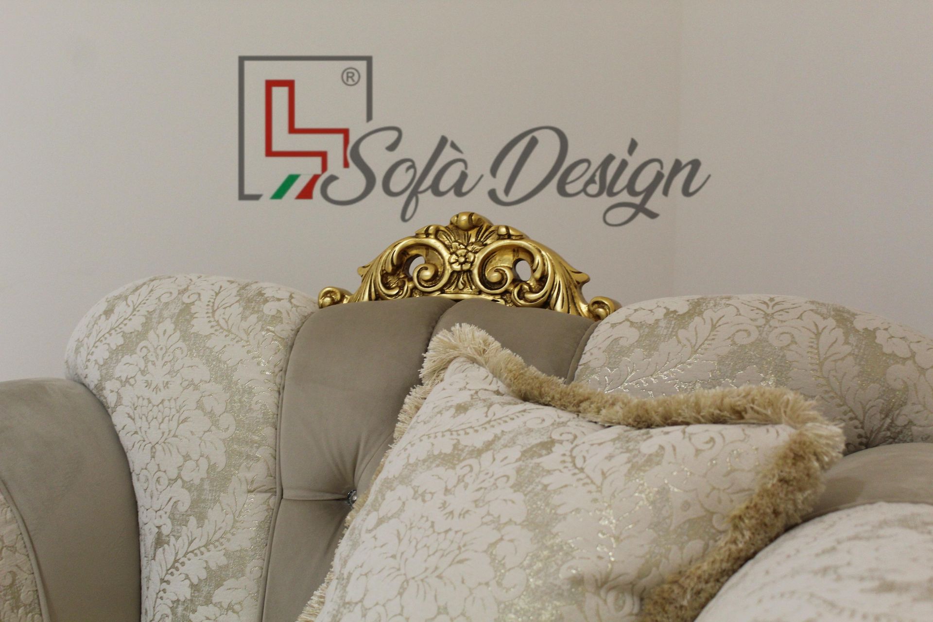 Primo piano di un divano decorativo con dettagli dorati e cuscini fantasia. Logo 