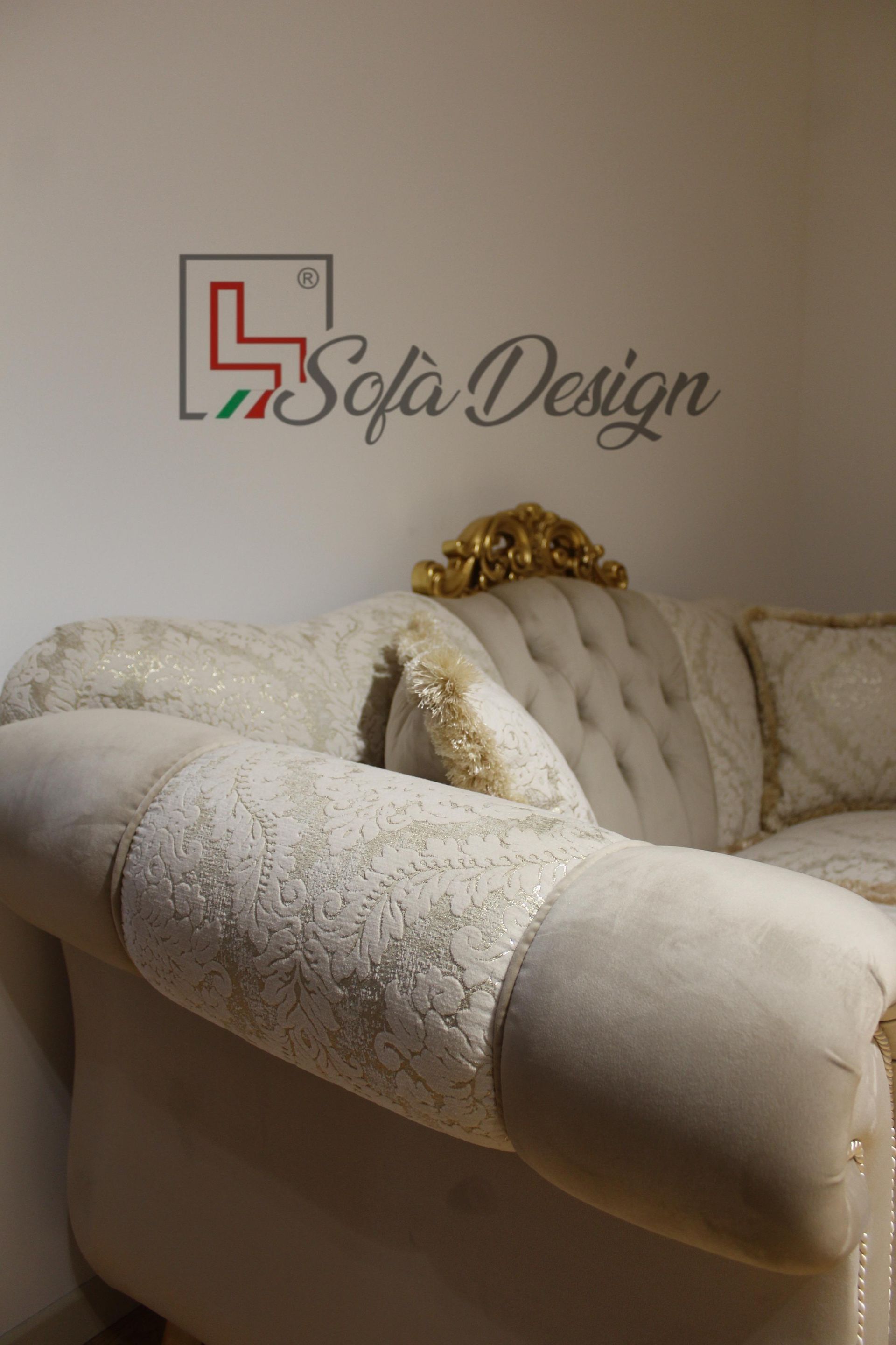 Divano beige con dettagli decorati contro una parete bianca; logo Sofa Design.