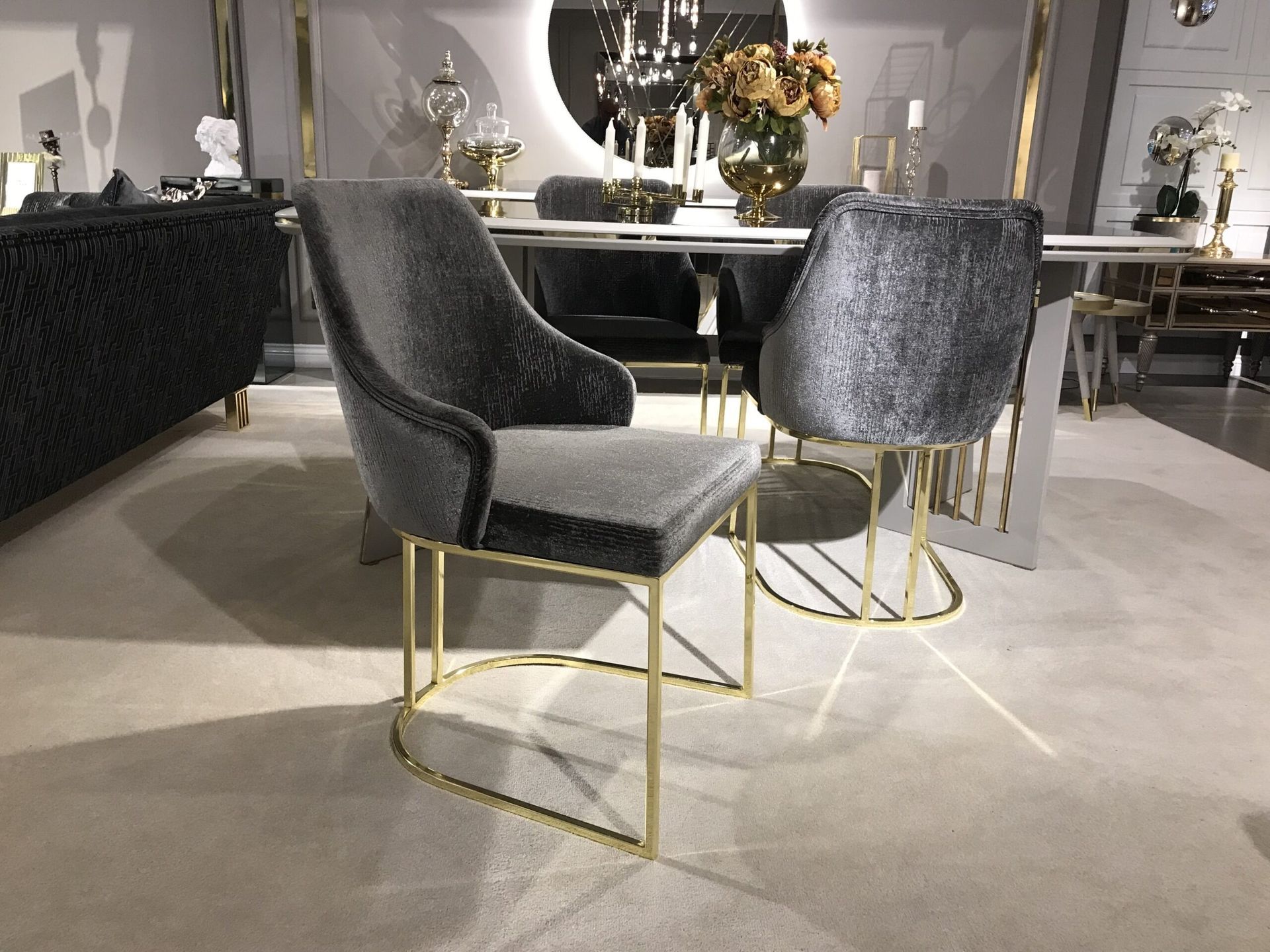Due sedie in velluto grigio con gambe dorate in una stanza con tavolo da pranzo e divano.