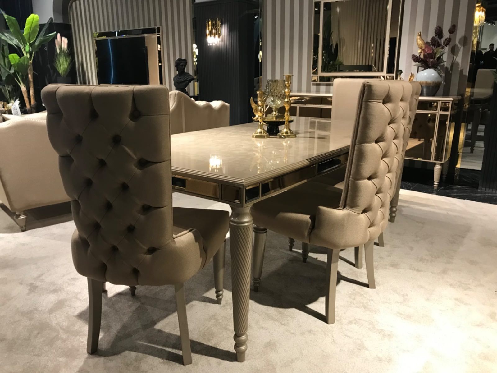 Sala da pranzo con sedie imbottite, tavolo riflettente e dettagli dorati.