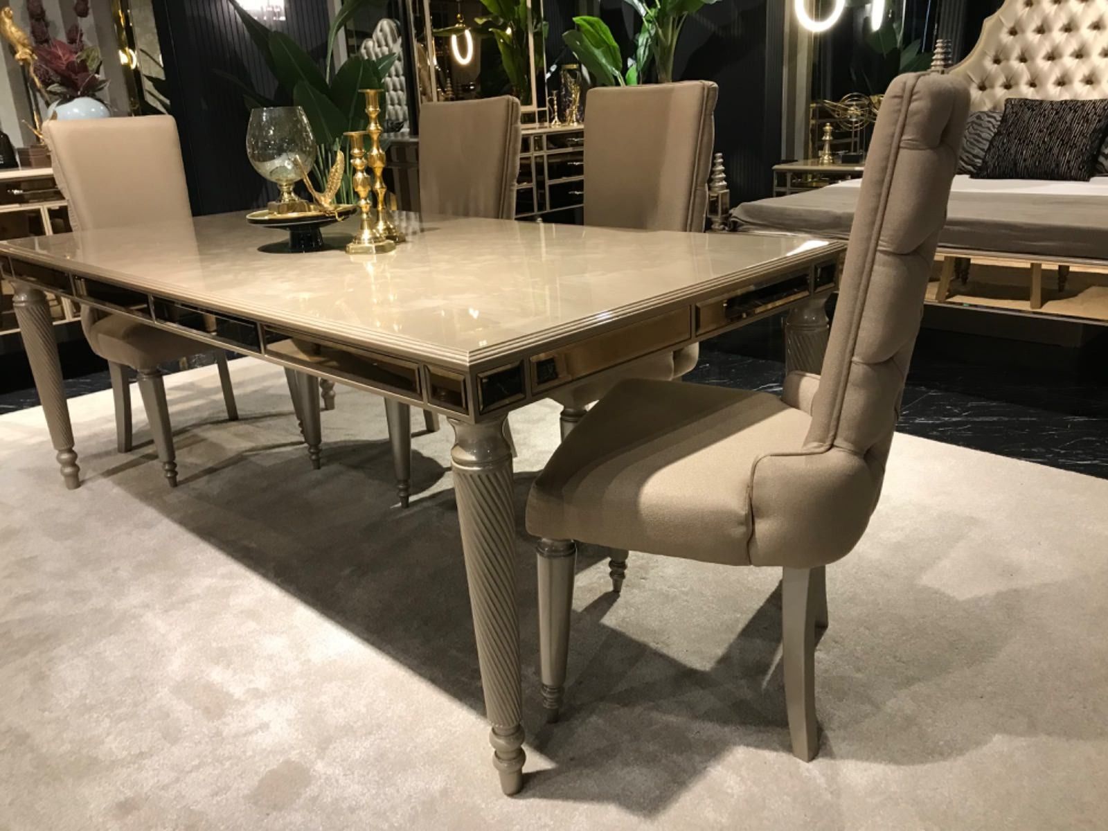 Un tavolo da pranzo con sei sedie beige. Il tavolo ha una superficie riflettente e finiture a specchio.