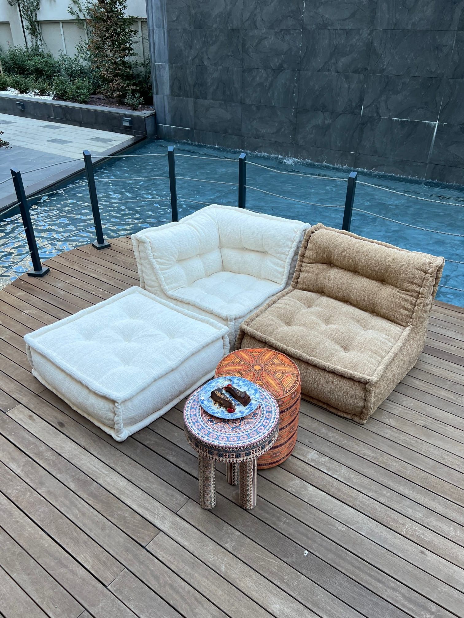 Bagno con doccia in marmo bianco, WC, mobiletto nero e tappeto. Una pianta è appoggiata sul coperchio del WC.