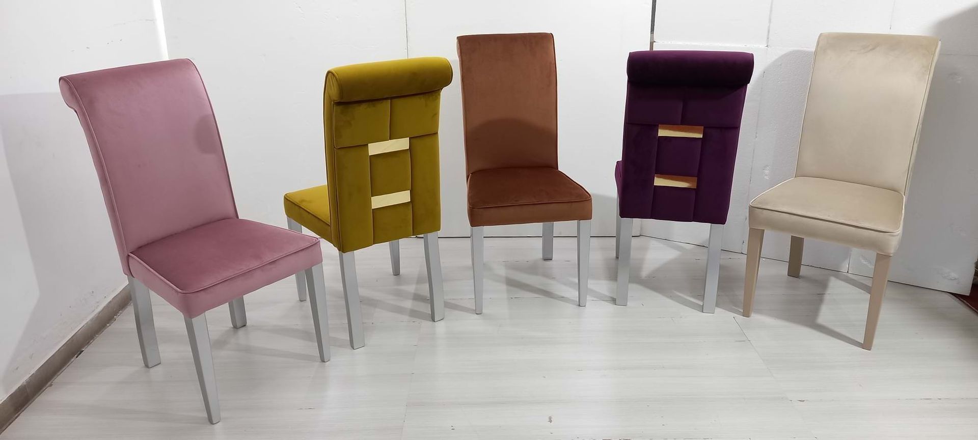 Cinque sedie da pranzo imbottite nei toni del rosa, giallo, marrone, viola e crema, con gambe argentate.