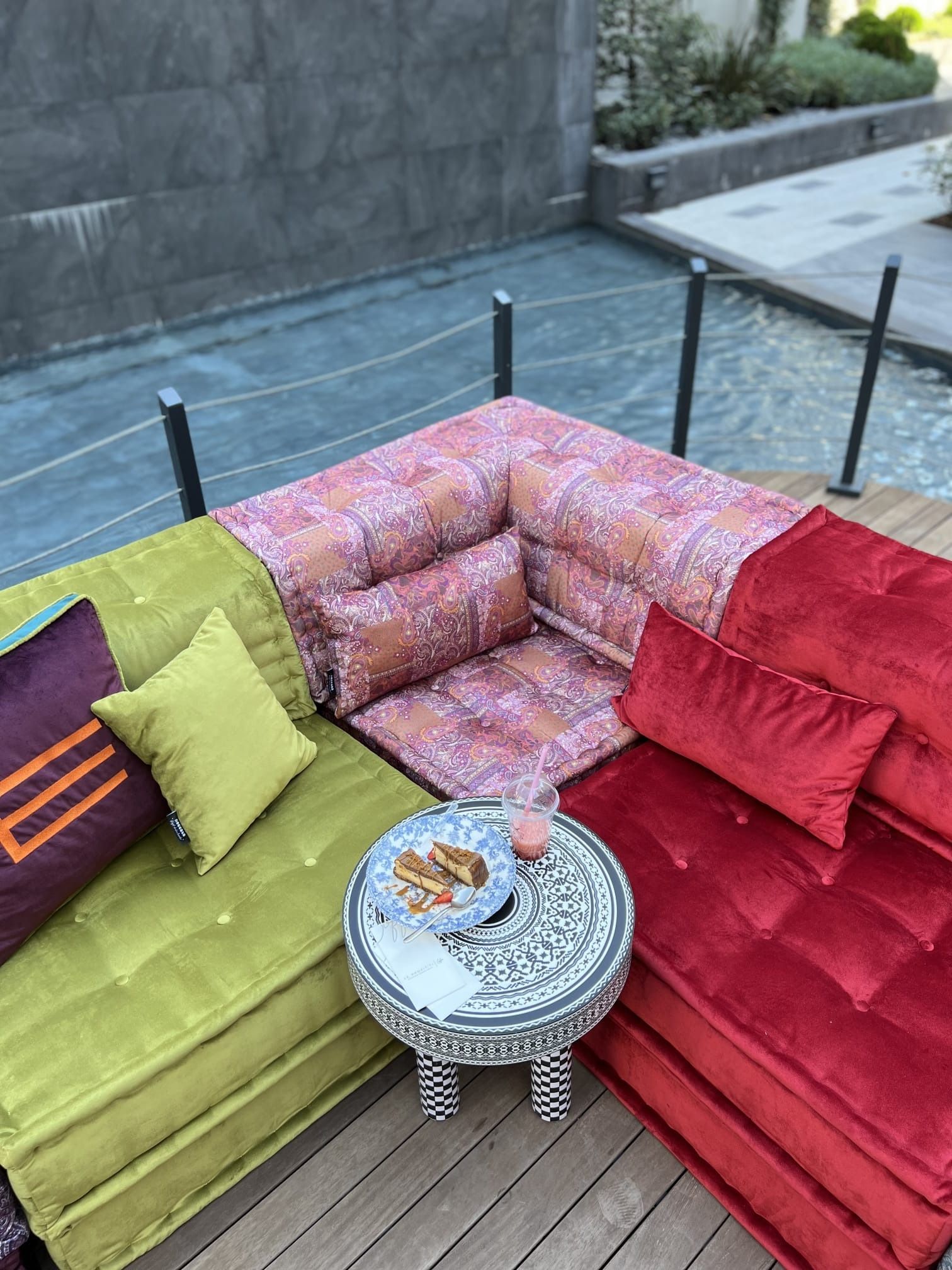 Divano componibile da esterno con cuscini colorati che circondano un tavolo con piano in mosaico.