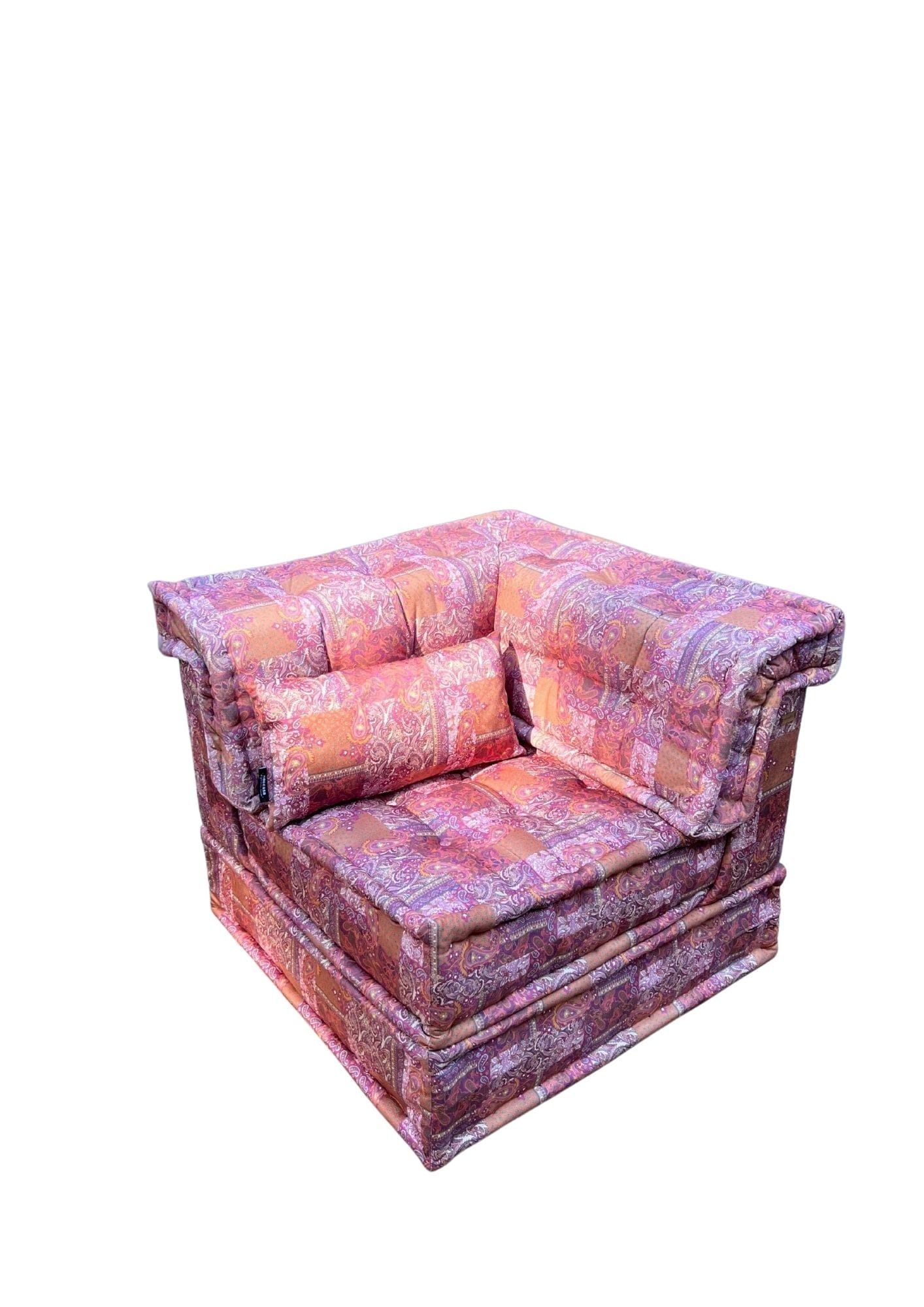 Poltrona con fantasia rossa e arancione, cuscino rettangolare e sfondo bianco.