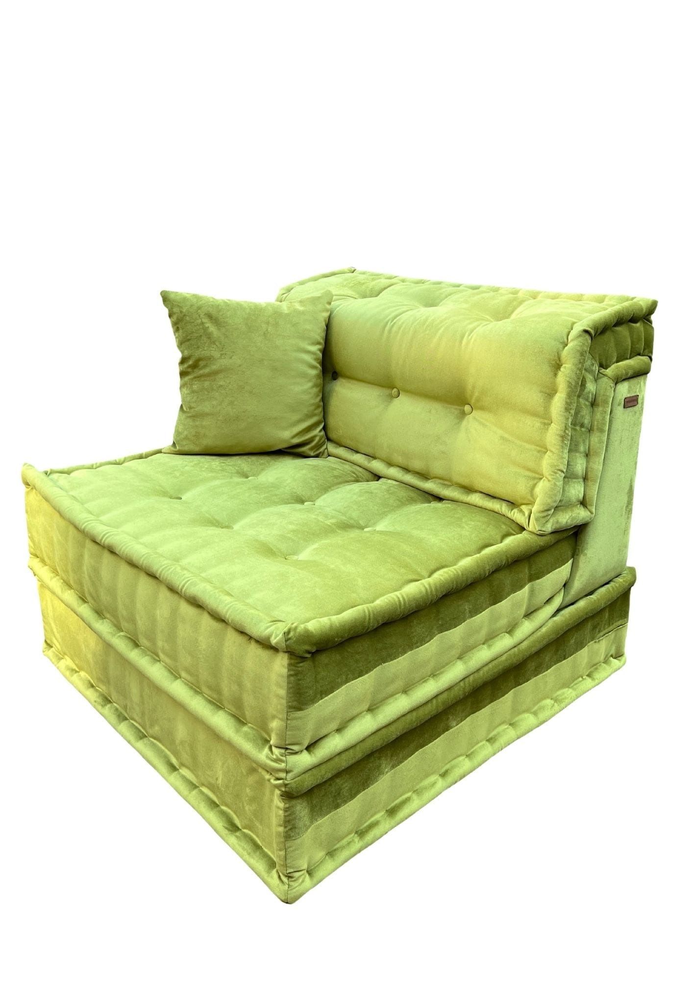 Divano modulare verde con seduta e schienale trapuntati, più un piccolo cuscino.