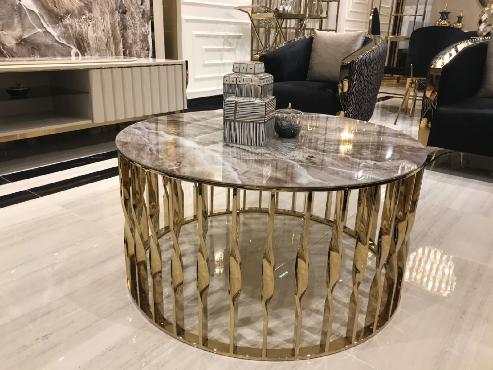 Tavolino rotondo con cornice dorata e piano in marmo in un lussuoso soggiorno.