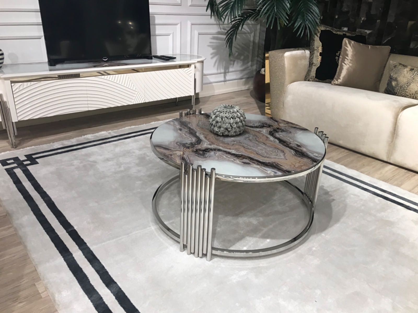 Soggiorno con divano color crema, tavolino da caffè con piano in marmo e mobile TV bianco.