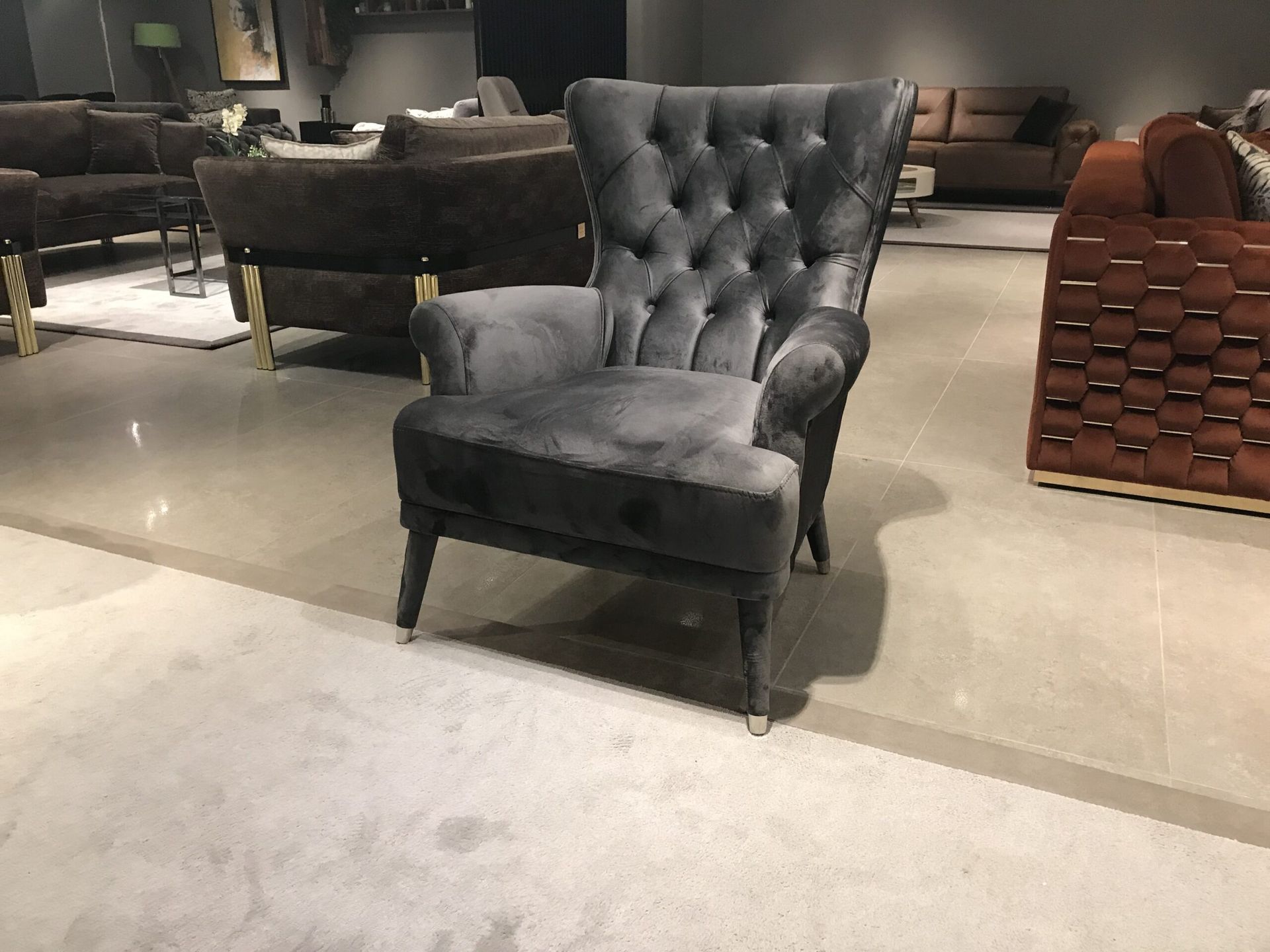 Poltrona in velluto grigio trapuntato in uno showroom.