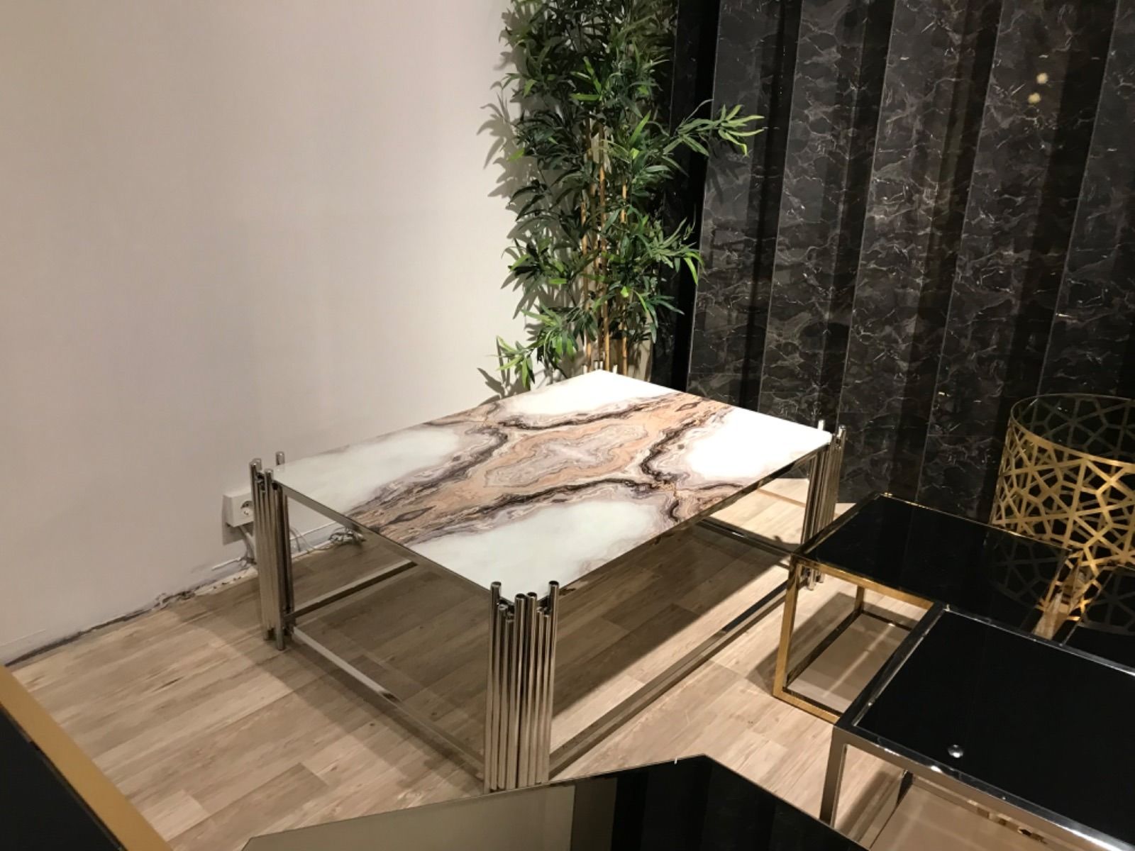 Tavolino con piano in marmo e struttura in acciaio inox. Arredamento moderno con piante e tavolini laterali.