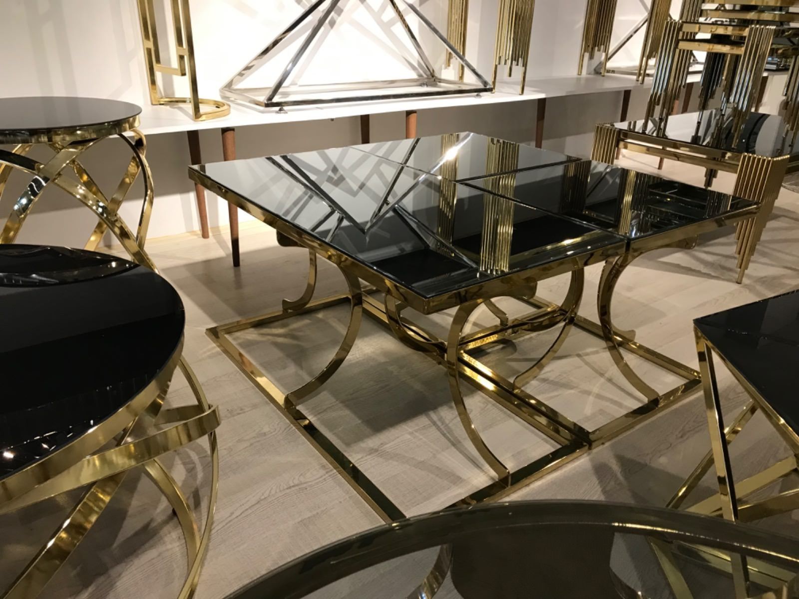 Tavoli con cornice dorata e piani in vetro nero in uno showroom.